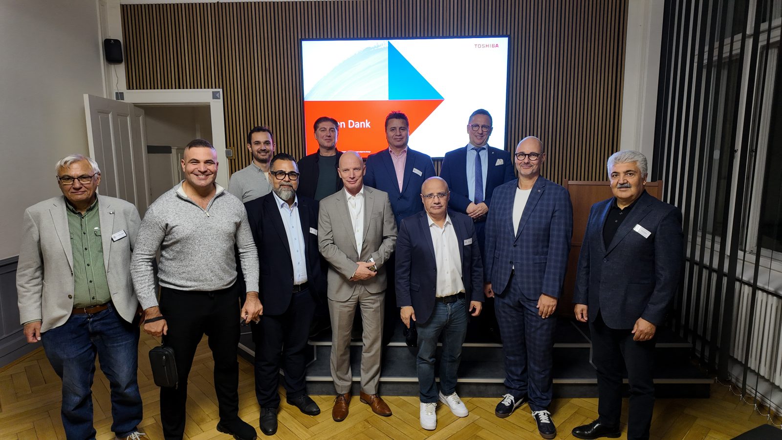 Gruppenfoto der Referenten und Gäste vor der Präsentationsleinwand im Saal der TDU